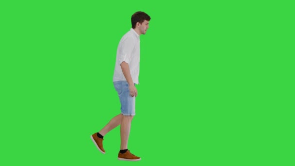 Уставший молодой человек, идущий и трогающий свою рубашку, страдая от летней жары на зеленом экране, Chroma Key. — стоковое видео