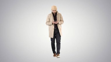 Pelerinli yakışıklı adam telefonda yürüyüp mesaj yolluyor.