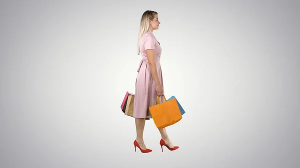 Menina bonita feliz segurando andando com sacos de compras no gradiente — Fotografia de Stock
