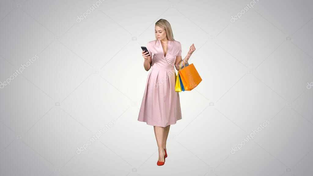 Shopping woman with bags texting message on smartphone while wal