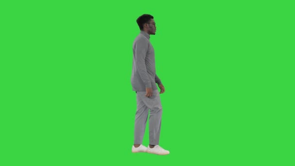 Hombre afroamericano joven en ropa casual gris caminando en una pantalla verde, Chroma Key. — Vídeos de Stock