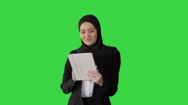 Pengusaha Arab dalam hijab menggunakan komputer tablet sambil berjalan dan tersenyum di depan kamera di layar hijau, Chroma Key. — Stok Video