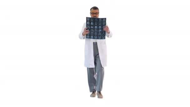Médico maduro caminando y revisando una resonancia magnética del cerebro sobre fondo blanco. — Vídeos de Stock