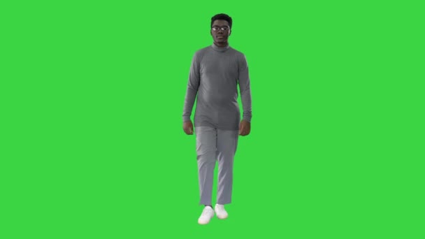 Hombre afroamericano joven en ropa casual gris caminando hacia la cámara en una pantalla verde, Chroma Key. — Vídeos de Stock