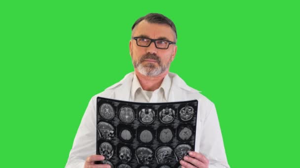 Концентрированный врач изучает рентгеновский снимок головного мозга на зеленом экране, хрома-ключ. — стоковое видео