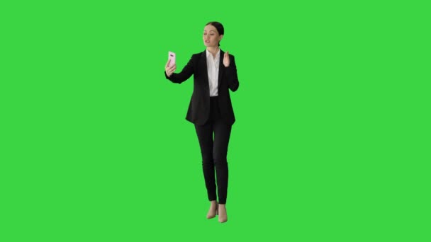 Νεαρή γυναίκα με κοστούμι που έχει επαγγελματική βιντεοκλήση στο τηλέφωνό της σε μια πράσινη οθόνη, Chroma Key. — Αρχείο Βίντεο