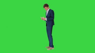 Mutlu iş adamı para sayıyor ve yeşil ekranda bir ceketin cebine sıkıştırıyor, Chroma Key..