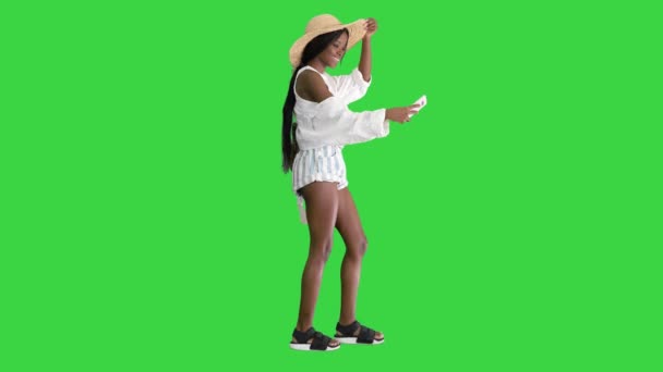 Улыбающаяся африканская американка в соломенной шляпе делает селфи во время прогулки по зеленому экрану, хрома-ключ. — стоковое видео