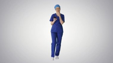 Düz bir arkaplanda akıllı telefonunu kullanan bir kadın doktor..