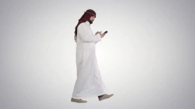 Arap şeyhi keffiyeh giyerek, gradyan arkaplanda telefonla ızgara haberi alıyor..