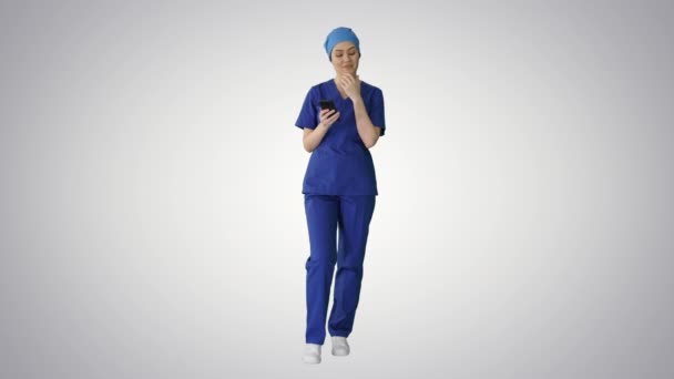 Thinking female doctor using her smartphone on gradient background. — Stock Video