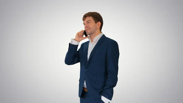 Bello giovane uomo d'affari che parla al telefono su gradiente indietro — Foto Stock