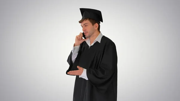 Male graduate in gown and mortarboard having conversation on the — Stock Photo, Image