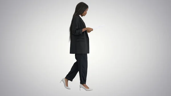 Mujer afroamericana seria leyendo documentos mientras camina o —  Fotos de Stock
