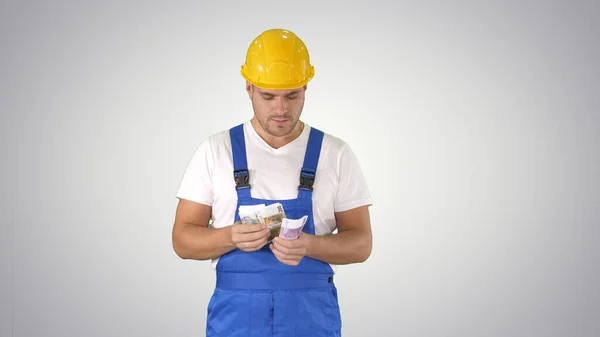 Builder tellen van geld staan op gradiënt achtergrond. — Stockfoto