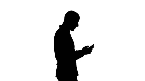 Silhouette Giovane uomo che cammina e utilizza un telefono. — Foto Stock