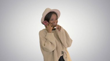 Örgü ve şapka giymiş gülümseyen Afro-Amerikan kadın konuşuyor.