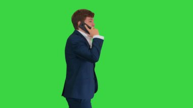 Yakışıklı genç işadamı yeşil ekranda yürürken telefonda konuşuyor, Chroma Key..