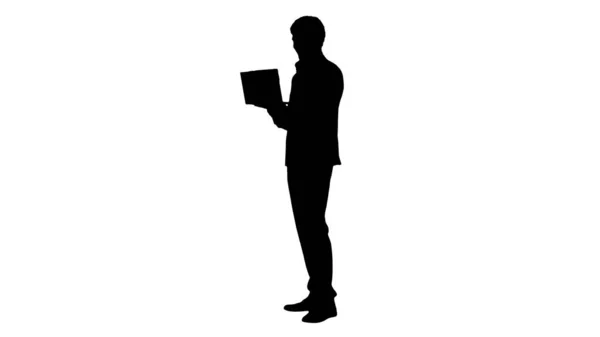 Silhouette Sorridente giovane uomo d'affari utilizzando il computer portatile mentre in piedi — Foto Stock