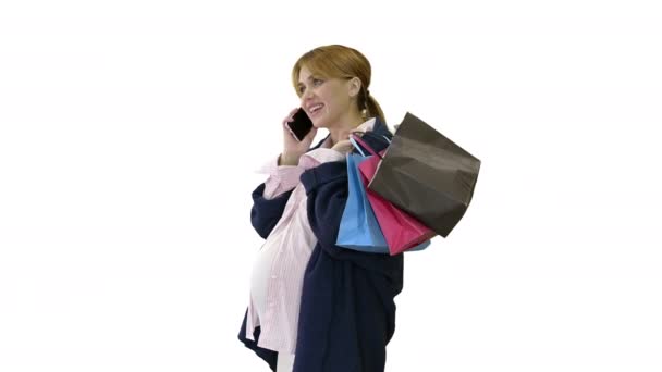 Feliz mujer embarazada de compras y hablando por teléfono sosteniendo bolsas sobre fondo blanco. — Vídeo de stock