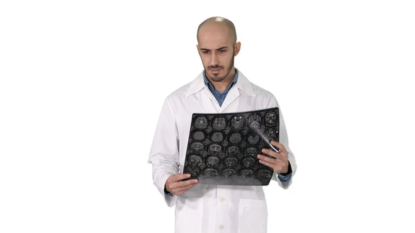 Arabischer Arzt begutachtet eine MRT-Untersuchung des Gehirns, während er auf weißem Hintergrund läuft. — Stockfoto