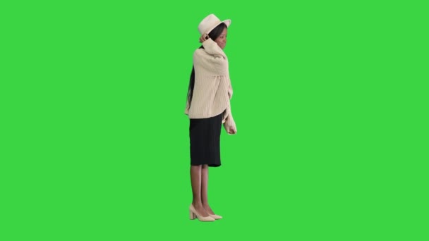 Módní africká americká žena pózující v pleteném a bílém klobouku na zelené obrazovce, Chroma Key. — Stock video