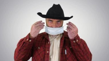 Kovboy, değişken arkaplanda korona virüsünü önlemek için tıbbi maske takıyor.