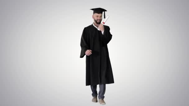 Végzős diák sétál és feldobja a kalapját gradiens háttér. — Stock videók