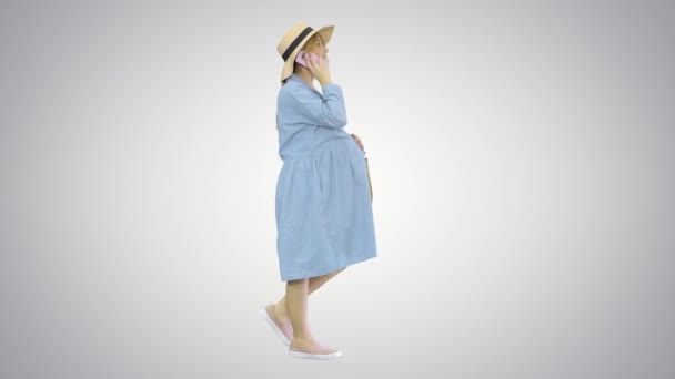 Beautiful caucasian pregnant woman making a call on summer walk outdoors on gradient background. — Stock Video