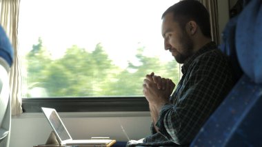 Heyecanlı adam trendeki tableti kontrol ediyor ve sonuçtan tatmin oluyor..