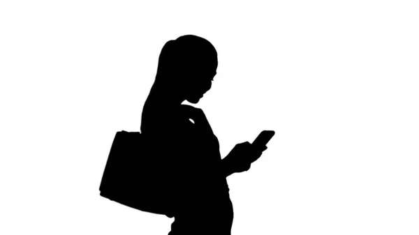 Silhuett Vacker ung kvinna med hjälp av en mobiltelefon promenader en — Stockfoto