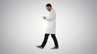 Yürüyen bir tıp uzmanı akıllı telefon kullanıyor ve tavan arası yapıyor.