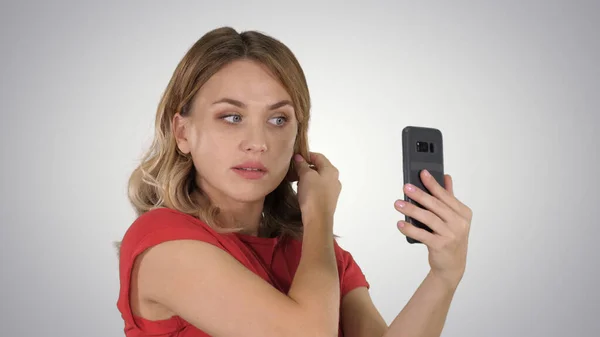 Mulher bonita preen usando seu telefone como um espelho no gradiente — Fotografia de Stock