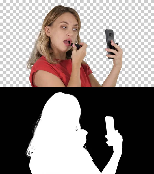 Blondine vrouw die lippenstift aanbrengt kijkend in de telefoon, Alpha Chann — Stockfoto