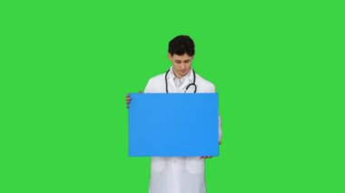 Gülümseyen erkek doktor steteskop takıyor ve yeşil ekranda boş bir poster tutuyor, Chroma Key.