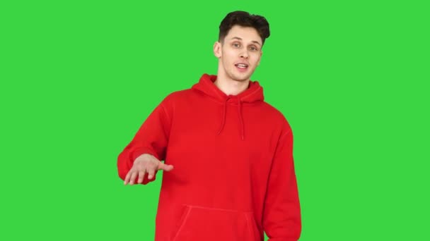 Νεαρός καυκάσιος χορευτής με κόκκινη κουκούλα που μιλάει στην κάμερα σε μια πράσινη οθόνη, Chroma Key. — Αρχείο Βίντεο