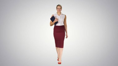 Kitapları tutan kadın kameraya doğru yürüyor.