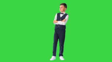 Papyonlu küçük bir çocuk kollarını kavuşturup yeşil ekrana bakıyor, Chroma Key..