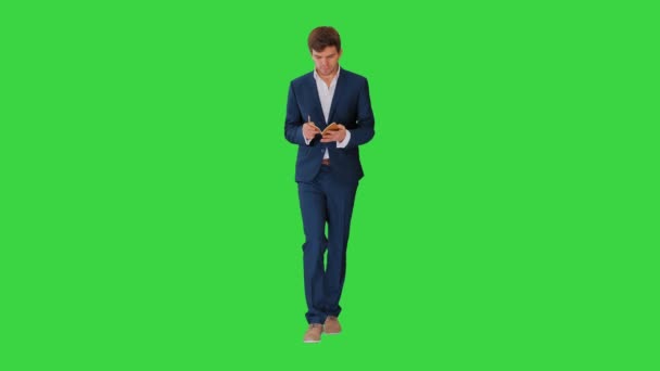 緑の画面を歩きながらノートを書くビジネスマンを考える、クロマキー. — ストック動画