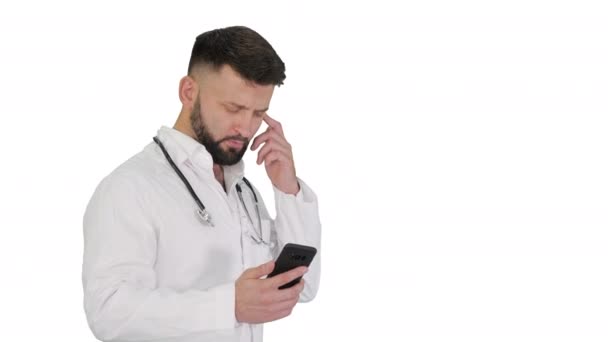 Médecin masculin en uniforme médical blanc marchant et utilisant smartphone sur fond blanc. — Video