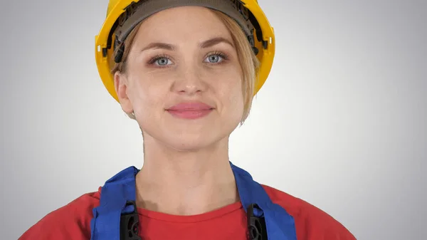 Mujer joven en hardhat amarillo caminando sobre fondo degradado. —  Fotos de Stock