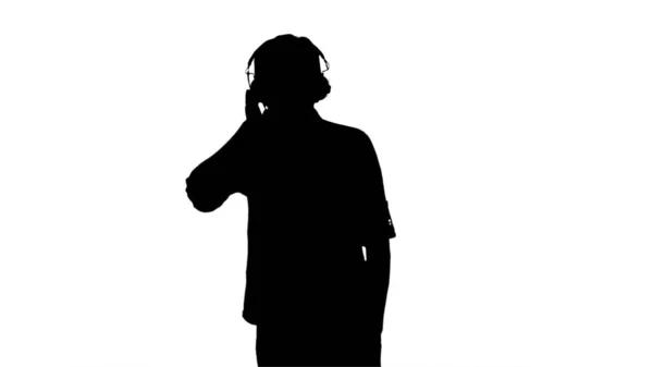 Silhouette Hombre joven casual escuchando música sosteniendo auriculares —  Fotos de Stock