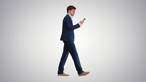 Empresário sério usando discagem por telefone durante a caminhada no fundo gradiente. — Vídeo de Stock