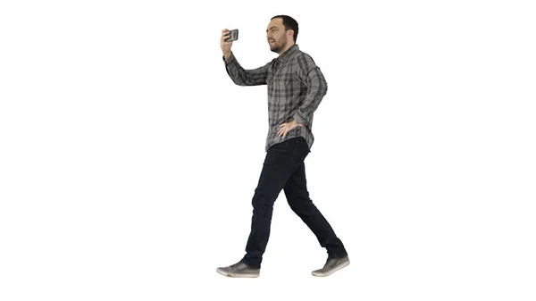 Young man taking photo with smartphone while walking on white ba — Stock Photo, Image