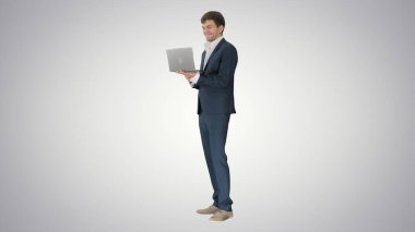 Gülümseyen genç işadamı gradien üzerinde dururken dizüstü bilgisayar kullanıyor