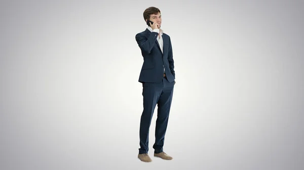 Bonito jovem empresário falando ao telefone no gradiente de volta — Fotografia de Stock