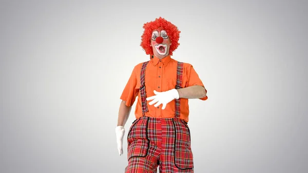 Clown loopt in een komische manier naar de camera op gradiënt terug — Stockfoto