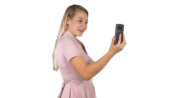 Kobieta w różowej sukience podejmowania rozmowy wideo ze swoim smartfonem na w — Zdjęcie stockowe