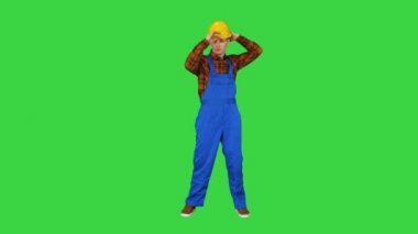 Bekar inşaat işçisi güvenlik şapkası takar ve yeşil ekranda dans eder, Chroma Key.