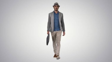 Sıradan bir Arap adam şapkasıyla ve mezuniyet çantasıyla yürüyor.